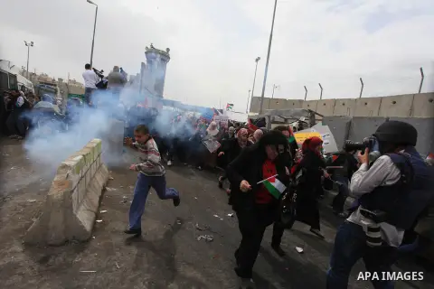 Palestinian women run from tear gas fired by Israeli troops at Qalandia checkpoint between Jerusalem and the West Bank city of Ramallah, Saturday, March 8, 2014. Palestinian women marked International Women's Day by marc...