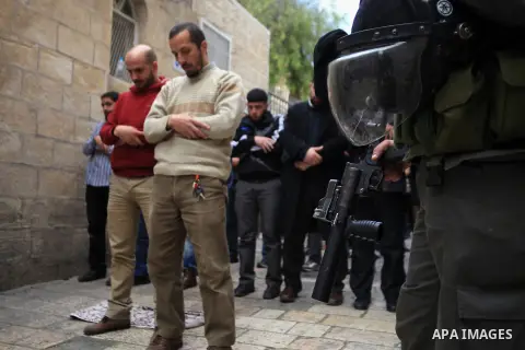 An Israeli policeman stands guard as Palestinians pray outside al-Aqsa mosque compound, in Jerusalem's Old City on March 11, 2014. Israeli authorities on Tuesday closed a number of Al-Aqsa Mosque compound gates and preve...