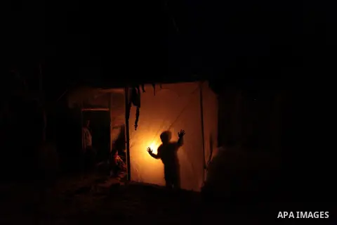 A Palestinian family sits inside their makeshift house during power cuts in Khan Younis in the southern Gaza Strip March 15, 2014. The Gaza Strip's sole power station stopped generating electricity on Saturday, causing b...