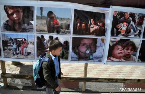 A Palestinian boy walks past a placard depicting the victims of blockade during a protest against the Egyptian-Israeli blockade on Gaza Strip, in Gaza City on March 16, 2014. Photo by Mohammed Talatene