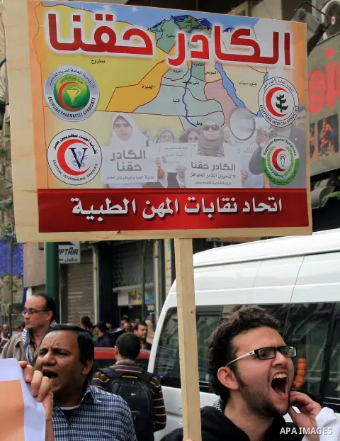 Egyptian doctors and pharmacists hold placards during a demonstration demanding for the application of the minimum wage, in Cairo on March 18, 2014. Egyptian medical professionals rejected the proposal of Minister of Hea...