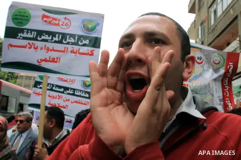 Egyptian doctors and pharmacists hold placards during a demonstration demanding for the application of the minimum wage, in Cairo on March 18, 2014. Egyptian medical professionals rejected the proposal of Minister of Hea...