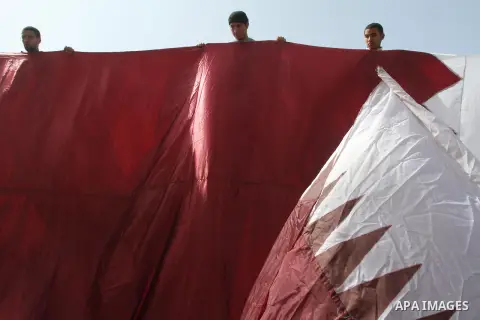 Palestinians hold a Qatari flag during a rally in Gaza city on March 19, 2014. The Emir of Qatar Sheikh Tamim bin Hamad Al Thani, spoke on Sunday with Palestinian Prime Minister in Gaza Strip, Ismail Haniyah, and told hi...