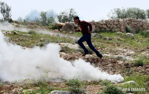 A Palestinian youth runs seek for cover from tear gas fired by Israeli security forces during clashes at the site where Palestinian youth Yussef Shawamreh was shot by Israeli forces near the West Bank village of Deir al-...