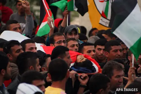Palestinian mourners carry the body of 15-year-old Yussef Sami Shawamreh, shot dead by Israeli troops, during his funeral in the village of Deir al-Asal al-Tahta, some 15 kilometres (nine miles) southwest of the West Ban...