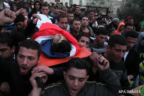 Palestinian mourners carry the body of 15-year-old Yussef Sami Shawamreh, shot dead by Israeli troops, during his funeral in the village of Deir al-Asal al-Tahta, some 15 kilometres (nine miles) southwest of the West Ban...