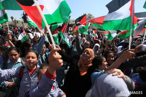 Palestinians wave their national flag as President Mahmud Abbas waves to his supporters following his trip to Washington DC, on March 20, 2014, in the West Bank city of Ramallah. US President Barack Obama and Palestinian...