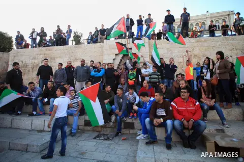 Palestinian demonstrators hold Palestinian flags on March 22, 2014 at Jerusalem's Damascus Gate leading into the Old City during a protest against the killing of three Palestinians were killed in Jenin refugee camp in th...
