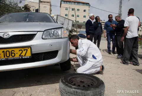 A Palestinian man changes the tyres of his car in an Arab neighborhood in Jerusalem, Monday, March 24, 2014. Israeli police say vandals have slashed car tires and sprayed a bus with hate graffiti in a predominantly Arab...