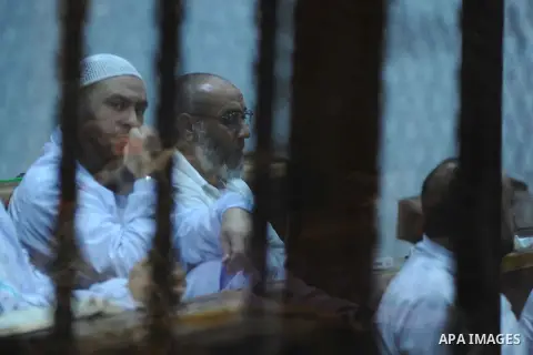 Egyptian suspects in the case of the 'Nasr City terrorist cell' look from inside the defendants cage during their trial, in Cairo on March 26, 2014. The suspects are charged with among others planning terrorist attacks a...