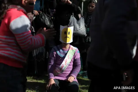 A Palestinian girl wears a sad face mask during an entertaining day to show solidarity with refugees children in Syria's main refugee camp Yarmouk, in Gaza City on March 27, 2014. Photo by Ashraf Amra