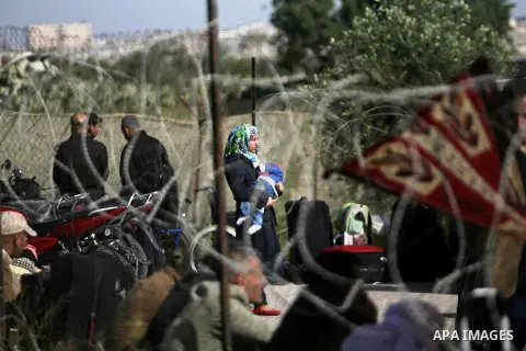 Palestinians hoping to cross into Egypt wait behind a barbed wire fence at the Rafah crossing between Egypt and the southern Gaza Strip March 29, 2014. Egyptian authorities partially reopened Rafah border crossing, Gaza'...