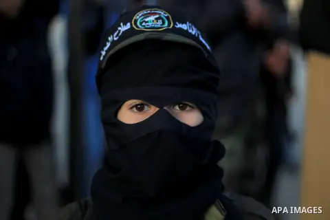 Masked militants of Al-Nasser brigades, the military wing of the Popular Resistance Committees, march with weapons during an anti-Israeli protest in Gaza City March 31, 2014. Photo by Khaled al-Sabbah
