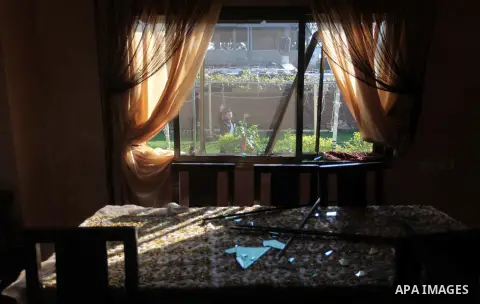 A Palestinian man is seen through a damaged house window following an overnight Israeli air strike on a nearby land in the central Gaza Strip April 4, 2014. After Israel called off the planned release of 26 Palestinian p...