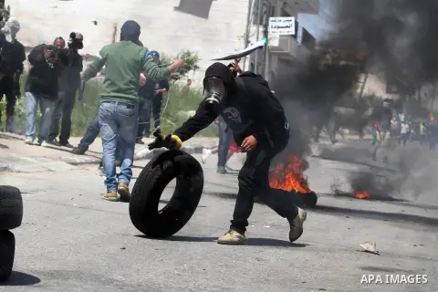 A Palestinian protester pushes a burning tyre during clashes with Israeli soldiers at a protest calling for the release of Palestinian prisoners held in Israeli jails, outside Israel's Ofer military prison near the West...