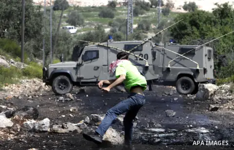 A Palestinian protester throws stones at Israeli security forces during clashes following a rally in support of Palestinian President Mahmoud Abbas in the village of Kfar Qaddum, near Nablus, in the occupied West Bank, A...