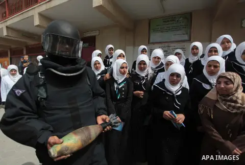 A member of Palestinian security forces carries a mortar shell as he explains to students the dangers of unexploded ammunition, at a school in Khan Younis in the southern Gaza Strip April 7, 2014. Photo by Ashraf Amra