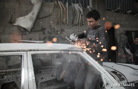 Twelve-year-old Palestinian boy Saher Totah works in a car workshop in Gaza City on April 7, 2014. There are about 65,000 working children in the Palestinian territories, accounting for 6% of all children at 5-14, accord...