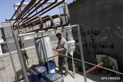 Palestinian Mahmoud Soboh, 28, works on a machine to extract fuel from plastic at a workshop in his house in Nuseirat refugee camp, central Gaza Strip, April 9, 2014. Soboh succeeded in production of fuel oil by the ther...