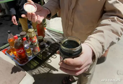 Palestinian Ibrahim Sobo, displays grease oil extracted from plastic at a workshop in his house in Nuseirat refugee camp, central Gaza Strip, April 9, 2014. Soboh succeeded in production of fuel oil by the thermal analys...