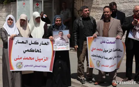 Palestinian journalists hold placards during a protest against the trial of the journalist Mohammed Mona, in front of the Red cross office in Gaza city, on April 9, 2014. Photo by Ashraf Amra