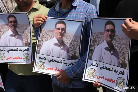 Palestinian journalists hold placards during a protest against the trial of the journalist Mohammed Mona, in front of the Red cross office in Gaza city, on April 9, 2014. Photo by Ashraf Amra