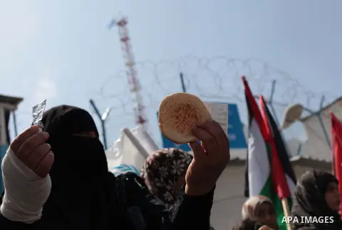 A Palestinian woman holds a bread during a protest a the decision made by the United Nations Relief and Works Agency (UNRWA) to reduce food aid delivered to the Gaza Strip in front of the UNRWA headquarters in Gaza City...