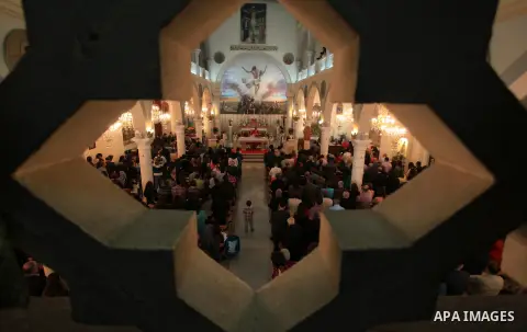 Palestinian Orthodox Christians attend the Palm Sunday mass at the Holy Family church in the West Bank city of Ramallah on April 13, 2014. Palm Sunday in many Christian churches symbolically marks the biblical account of...