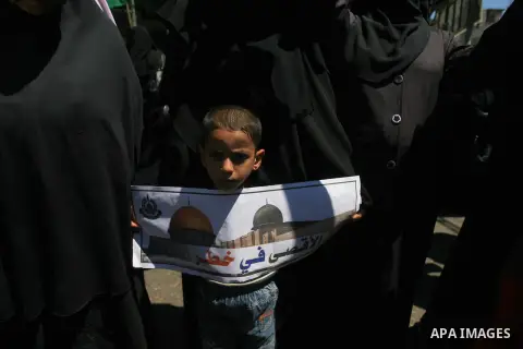 A Palestinian boy holds banners during a rally to show solidarity with al-Aqsa mosque, in Rafah in the southern Gaza Strip April 14, 2014. The Palestinian presidency warned on Sunday against the continuous breaking into...