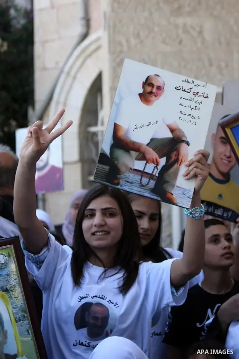 Palestinians hold pictures of prisoners held in Israeli jails during a rally marking Palestinian Prisoners' Day in Jerusalem on April 17, 2014. Thousands of Palestinians across the West Bank and Gaza rallied in solidarit...