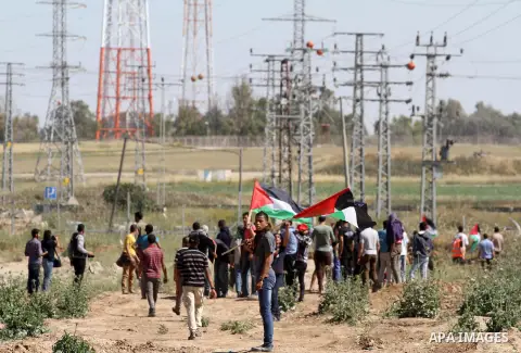 Palestinian protestors wave their national flags in front of Israeli security forces during a demonstration in solidarity with prisoners held in Israeli jails, near Nahal Oz border crossing with Israel, east of Gaza City...