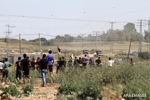 Palestinian protestors wave their national flags in front of Israeli security forces during a demonstration in solidarity with prisoners held in Israeli jails, near Nahal Oz border crossing with Israel, east of Gaza City...
