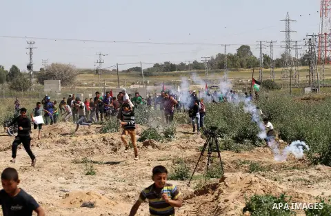 Palestinian protestors wave their national flags in front of Israeli security forces during a demonstration in solidarity with prisoners held in Israeli jails, near Nahal Oz border crossing with Israel, east of Gaza City...