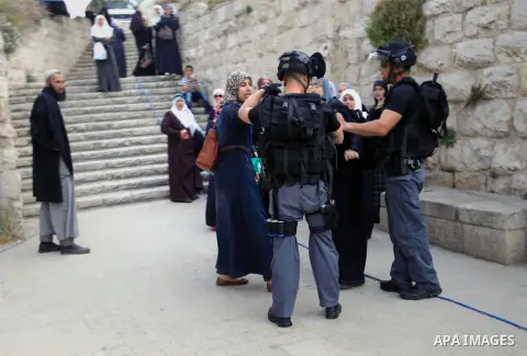 Palestinian Muslim worshippers wait next to Israeli border guards to have their documents and belongings checked at the entrance of the Al-Aqsa mosque compound in Jerusalem's Old City, April 20, 2014. Dozens of Palestini...