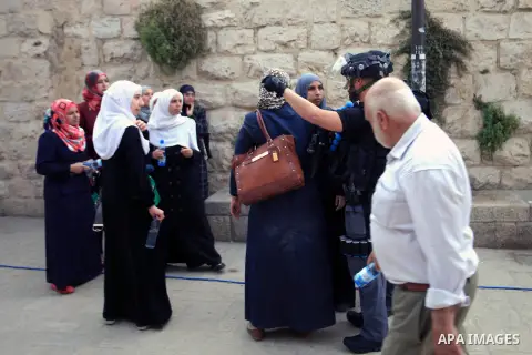 Palestinian Muslim worshippers wait next to Israeli border guards to have their documents and belongings checked at the entrance of the Al-Aqsa mosque compound in Jerusalem's Old City, April 20, 2014. Dozens of Palestini...