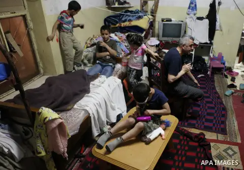 A Palestinian man with his children inside thier house in Kafr near the West Bank city of Ramallah on April 25, 2014. Al-Kurdi poor family consist of 8 members who face difficult life and the high cost of living. Photo b...