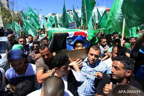 Palestinian mourners wave the green flag of the Islamist movement Hamas as they attend the funeral of two Hamas members, Adel and Imad Awadallah, killed in 1998, after Israel returned the remains of four Palestinians to...