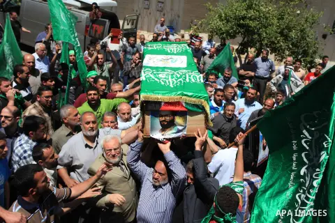 Palestinian mourners wave the green flag of the Islamist movement Hamas as they attend the funeral of two Hamas members, Adel and Imad Awadallah, killed in 1998, after Israel returned the remains of four Palestinians to...