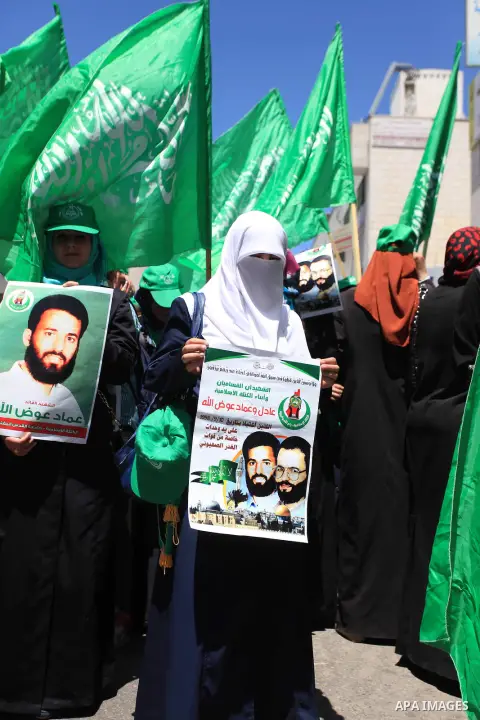 Palestinian mourners wave the green flag of the Islamist movement Hamas as they attend the funeral of two Hamas members, Adel and Imad Awadallah, killed in 1998, after Israel returned the remains of four Palestinians to...