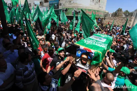 Palestinian mourners wave the green flag of the Islamist movement Hamas as they attend the funeral of two Hamas members, Adel and Imad Awadallah, killed in 1998, after Israel returned the remains of four Palestinians to...