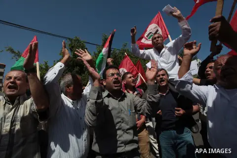 Palestinian labors chant slogans as others hold bowls during a march for the International Labor Day in Gaza City, Thursday, May 1, 2014. According to the United Nations Office for the Coordination of Humanitarian Affair...