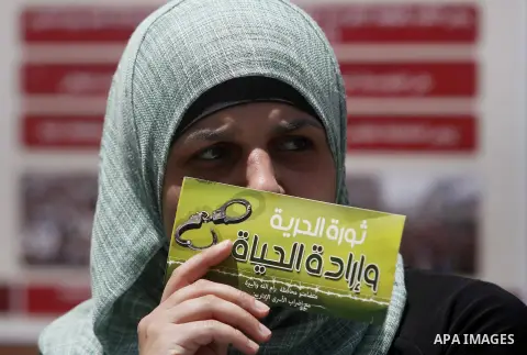 A Palestinian woman holds Placard of a Palestinian held in an Israeli jail during a demonstration in the West Bank city of Ramallah in support of prisoners on hunger strike on May 3, 2014. Photo by Issam Rimawi
