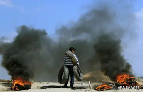 A Palestinian youth carries tires during clashes with Israeli security forces near the border with Israel, east of Jabalia refugee camp in northern Gaza Strip, May 21, 2014 .Rallies in support of the hunger-striking pris...