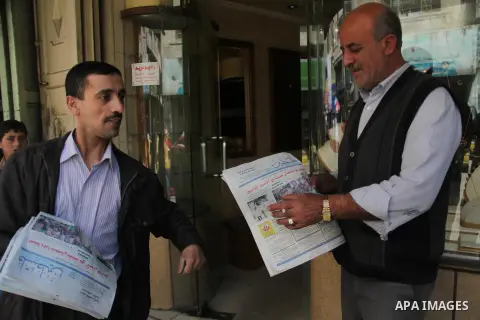 Palestinian men read a copy of the Palestine newspaper in the West Bank city of Hebron, on May 10, 2014. Palestinian government in Ramallah allowed the redistribution of a West Bank based Palestine newspaper in the West...