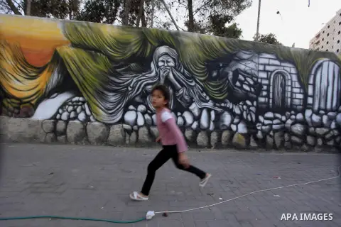 A Palestinian girl walks past a mural depicts "Nakba of the Palestinian child" on a wall marking the 66 anniversary of Nakba or the ''Day of Catastrophe'' in the Qalandia refugee camp near the West Bank city of Ramallah,...