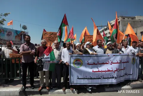 Palestinians shouts slogans and wave their national flag during a demonstration supporting a new attempt to reconcile the militant Islamist movement Hamas and the Palestine Liberation Organisation (PLO) in Gaza City on M...