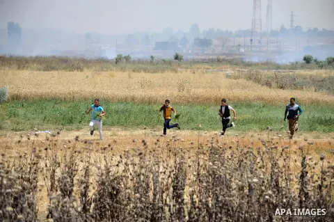 Palestinian protesters run from tear gas fired by Israeli security forced during a demonstration marking the Nakba or the ''Day of Catastrophe'' near the Nahal Oz crossing east of Gaza City on May 15, 2014. Palestinians...