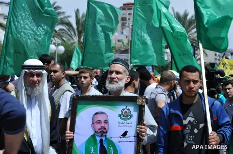 Palestinians hold banners during a demonstrator calling for the end of administrative detention as others wave their national flag in Gaza City on May 16, 2014 after Friday prayers to express solidarity with Palestinian...