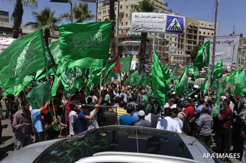 Palestinian supporters of Hamas wave the green flag of the Islamist movement and pictures of Palestinian prisoners during a rally in the West Bank city Ramallah on May 17, 2014 to express solidarity with Palestinian pris...