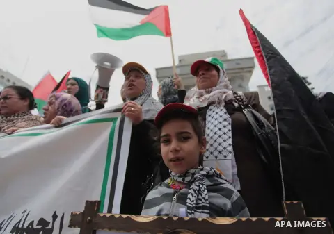 Palestinians hold placards and Palestine flags during a demonstration to calling for an end in the political division and the national reconciliation in Gaza city, on May 20, 2014. Photo by Ashraf Amra